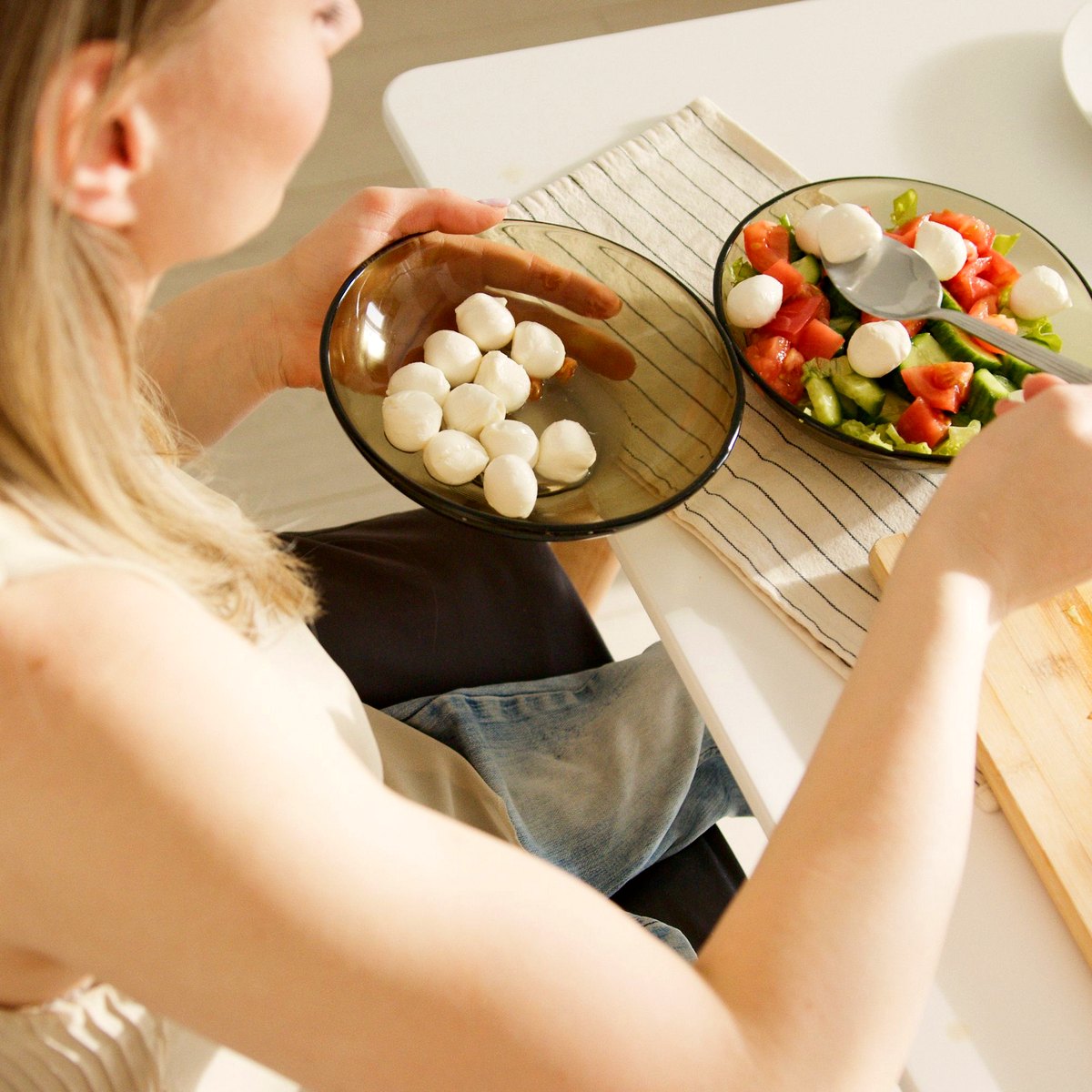Person preparing a salad at a kitchen table from a wheelchair